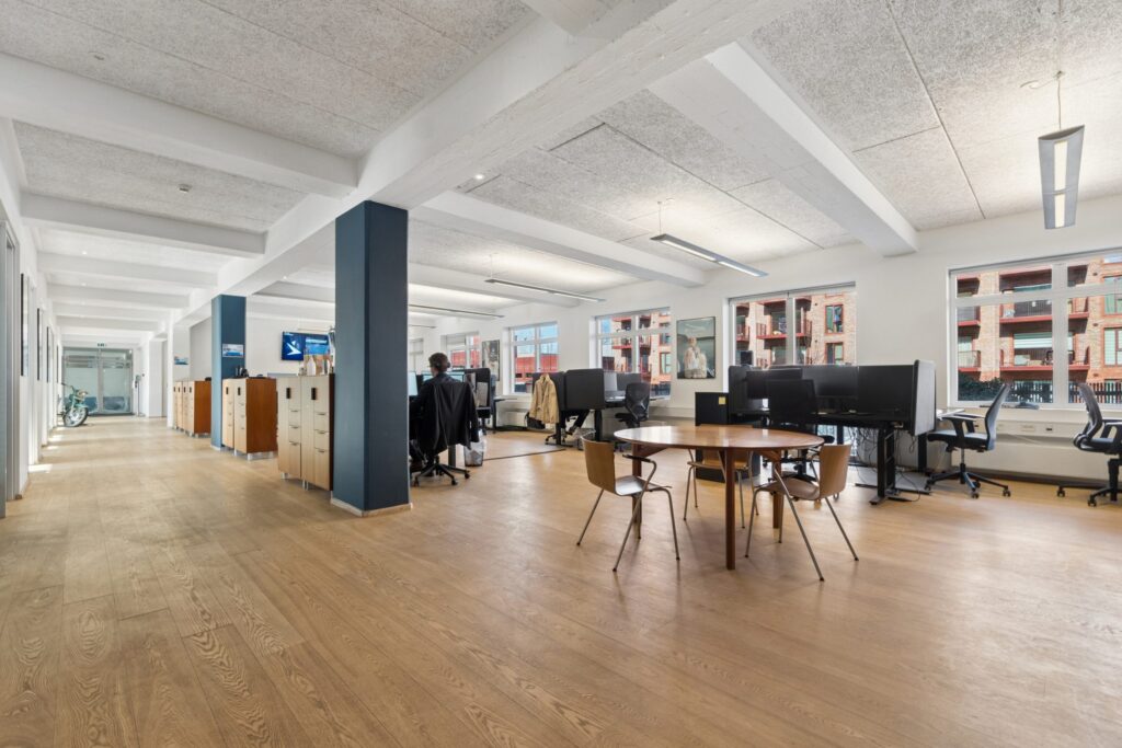 Moderne kontormiljø i Kirkebjerg Vigespor med lyse arbejdsrum og bevarede industrielle detaljer.
