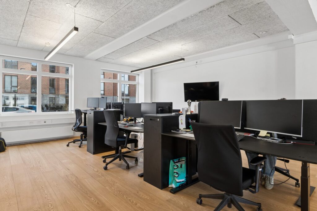 Moderne kontormiljø i Kirkebjerg Vigespor med lyse arbejdsrum og bevarede industrielle detaljer.